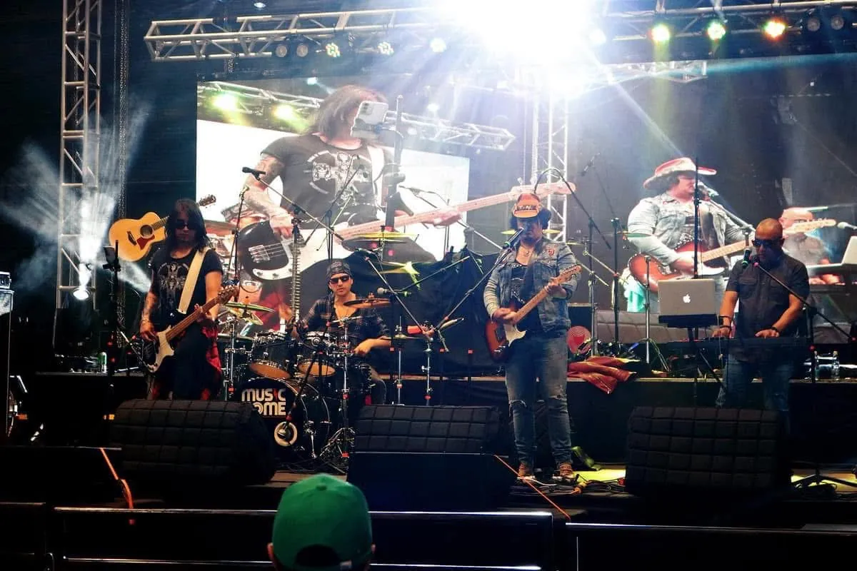 Mateo Acevedo y su banda completa tocando en la tarima de un festival con pantalla gigante.