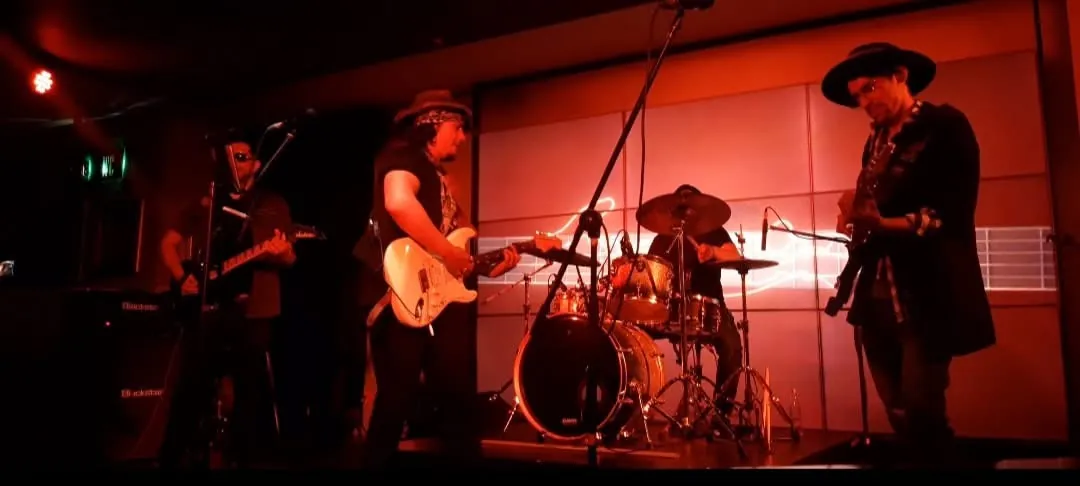 Mateo Acevedo y su banda en vivo sobre el escenario, iluminados con luces rojas durante un show de rock.