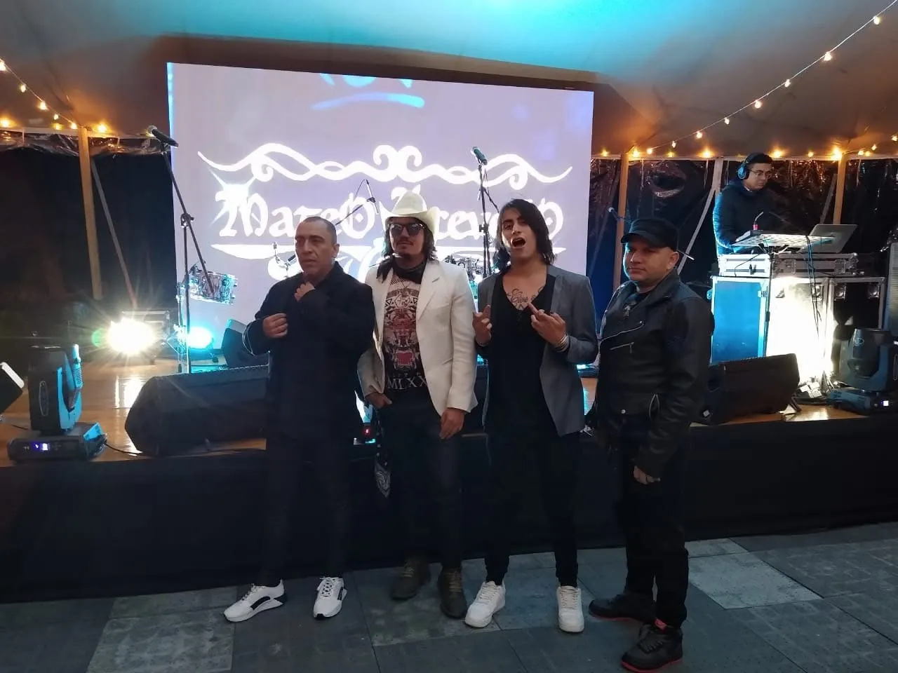 Mateo Acevedo y su banda posan frente a la pantalla con su logo durante un evento en vivo.