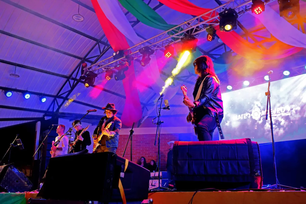 Mateo Acevedo y su banda en una tarima al aire libre con luces de colores festivas.