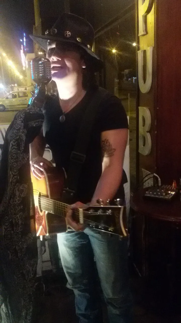 Mateo Acevedo tocando guitarra en vivo en un bar con luces cálidas