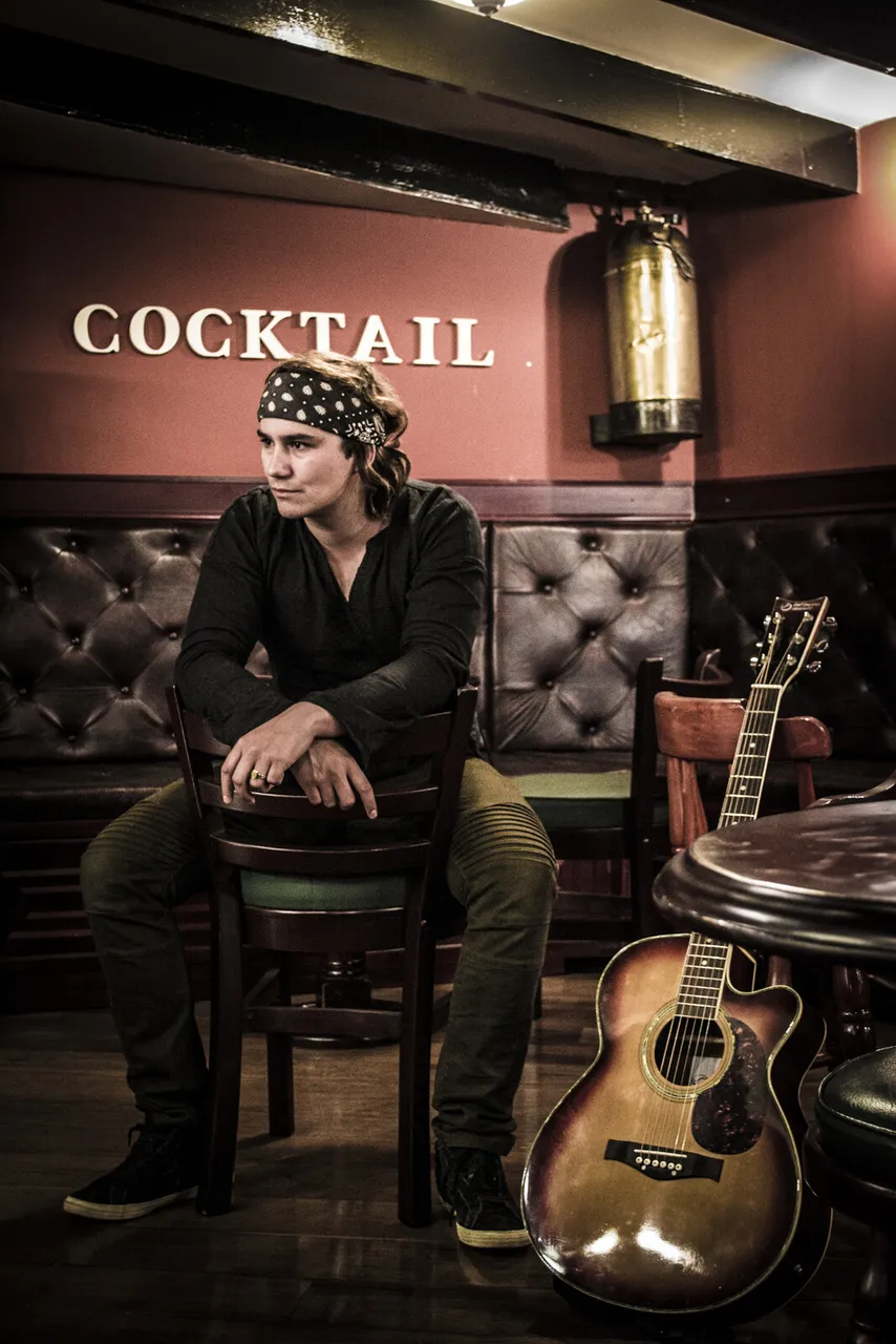 Mateo Acevedo sentado con una guitarra acústica en un bar lounge