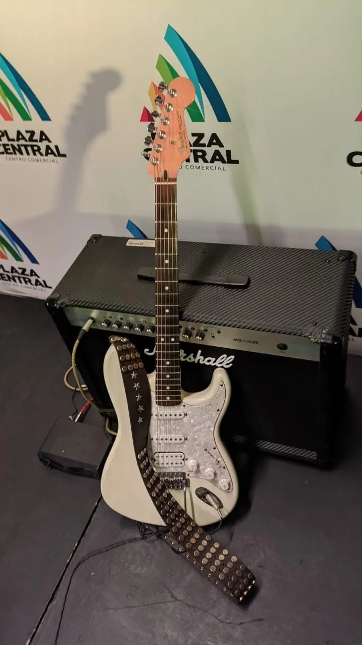 Guitarra eléctrica blanca de Mateo Acevedo apoyada en un amplificador, lista para la presentación.