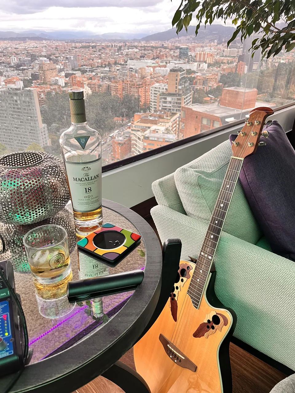 Guitarra acústica apoyada en una terraza con vista panorámica de Bogotá, junto a copas para un evento privado.