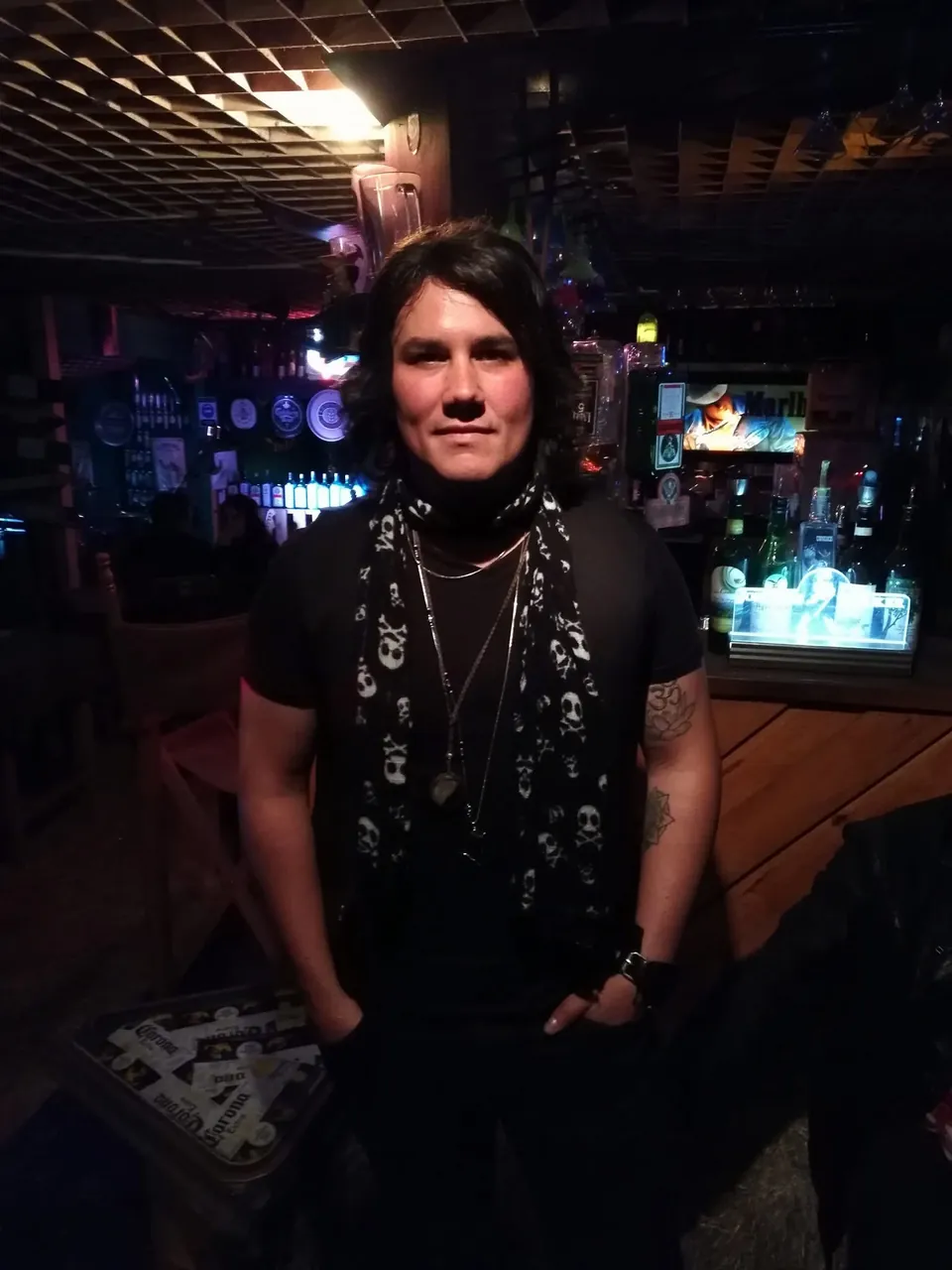Retrato de Mateo Acevedo, cantante de rock, posando con pañuelo de calaveras y tatuajes dentro de un bar.