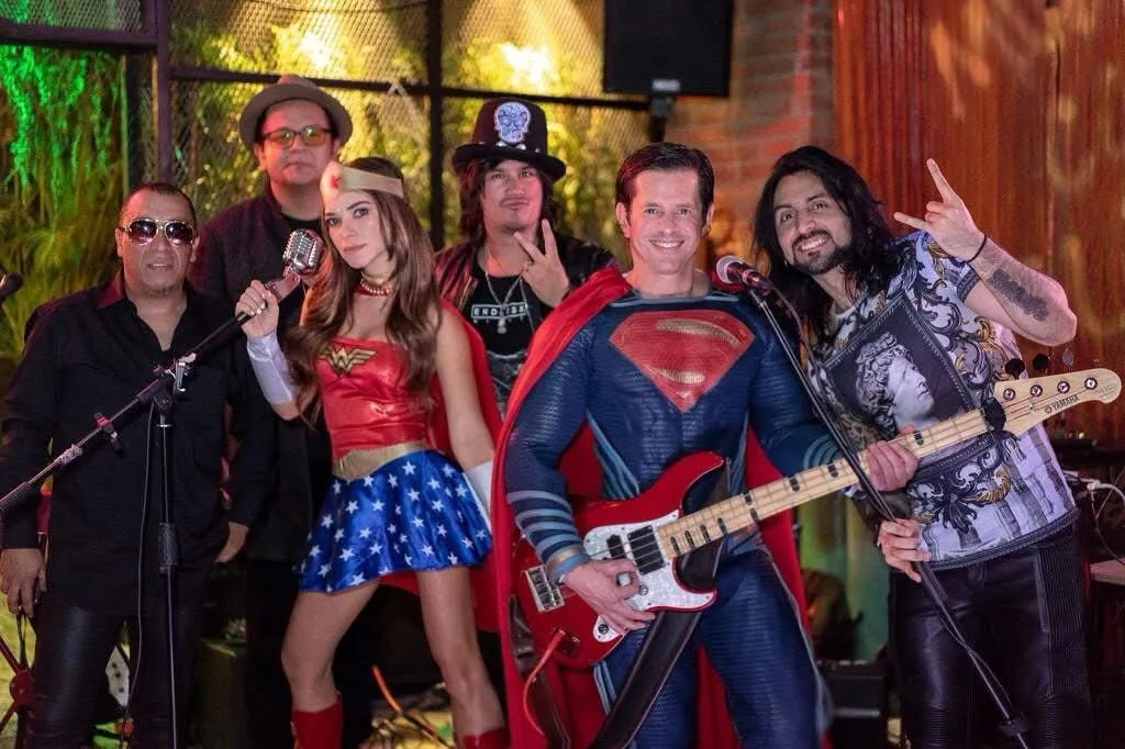 Mateo Acevedo con su banda en un show tributo temático con disfraces de superhéroes durante un evento.